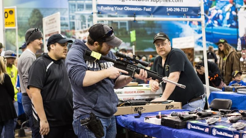 A vendor looks on as a customer handles a scoped rifle at a gun show on Sunday, March 25. A...