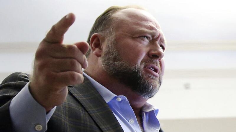 FILE - Alex Jones talks to media during a midday break in his trial at the Travis County...
