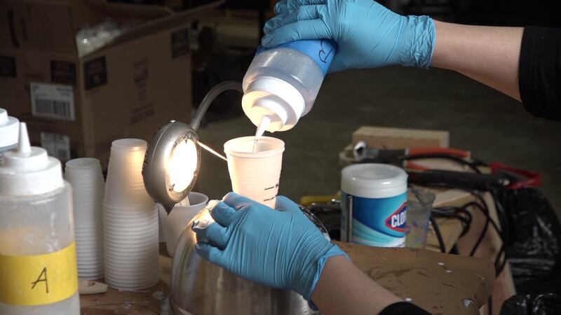 A makespace volunteer prepares resin to pour into the shield mold.